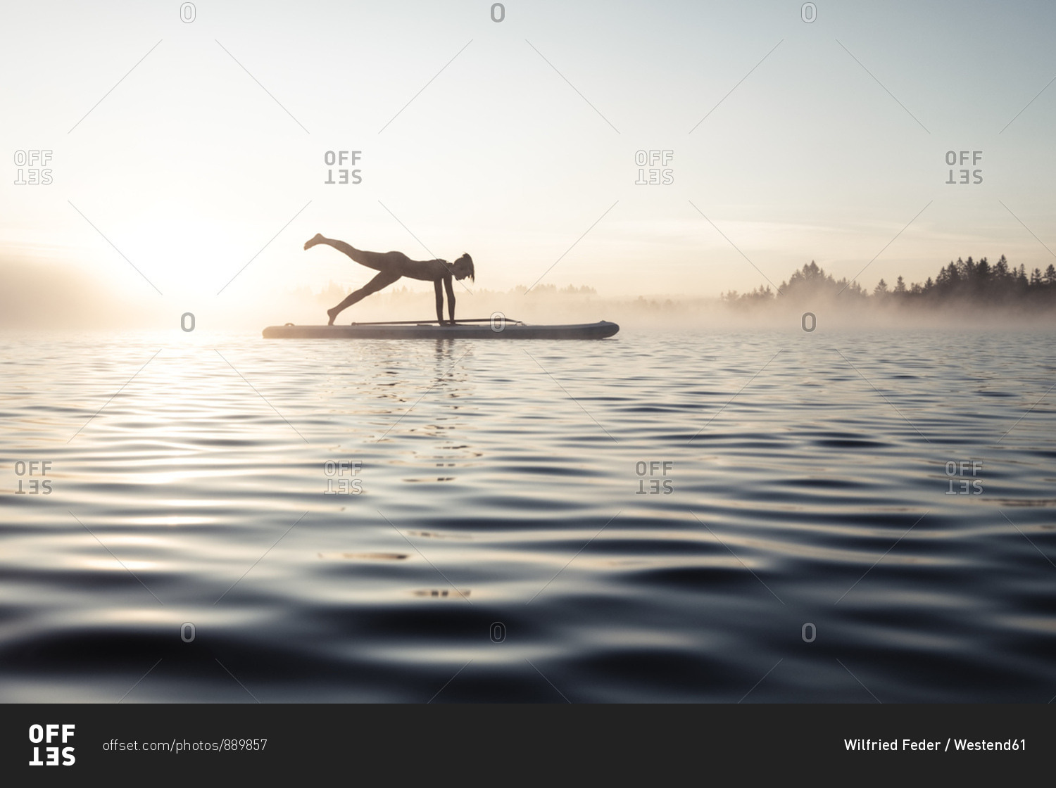 Woman practicing paddle board yoga on lake Kirchsee in the morning- Bad Toelz- Bavaria- Germany