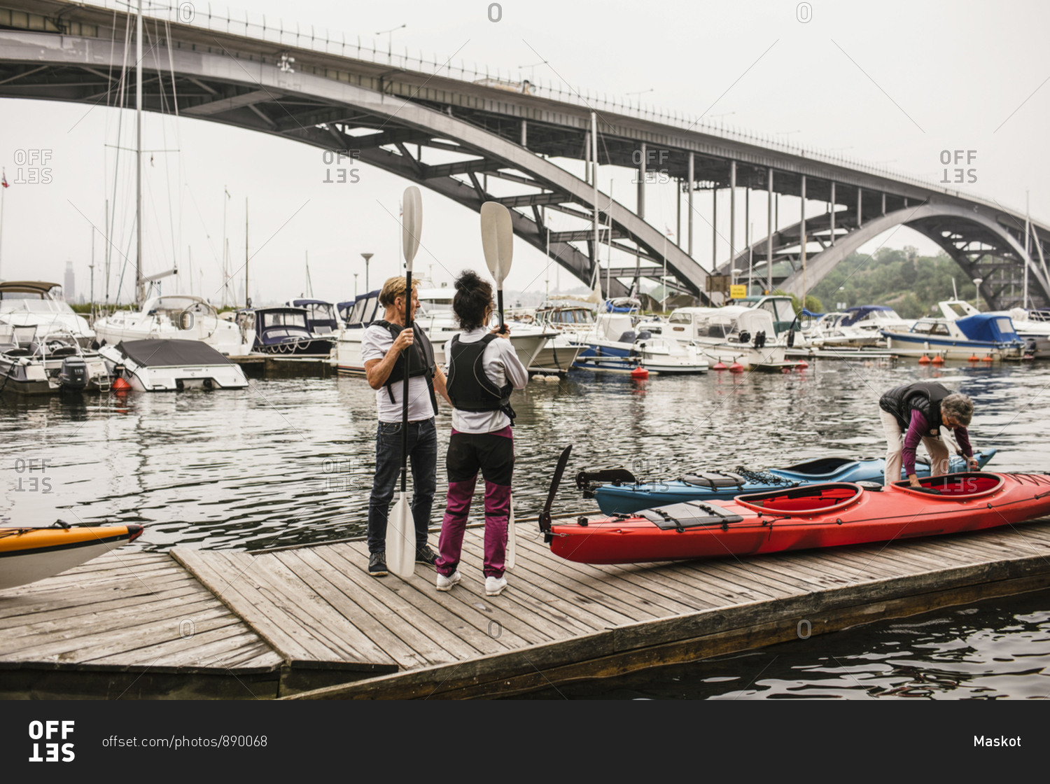 Senior male and females with kayaks and paddles on jetty during kayaking course