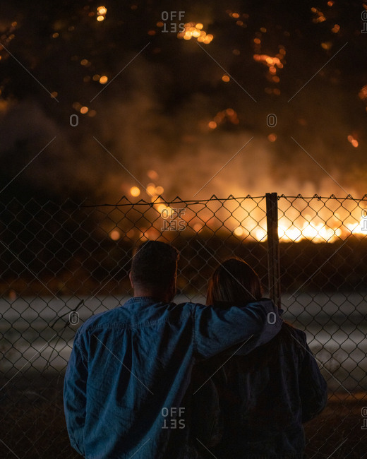 A couple embraces as a wildfire burn near a highway in Los Angeles, CA