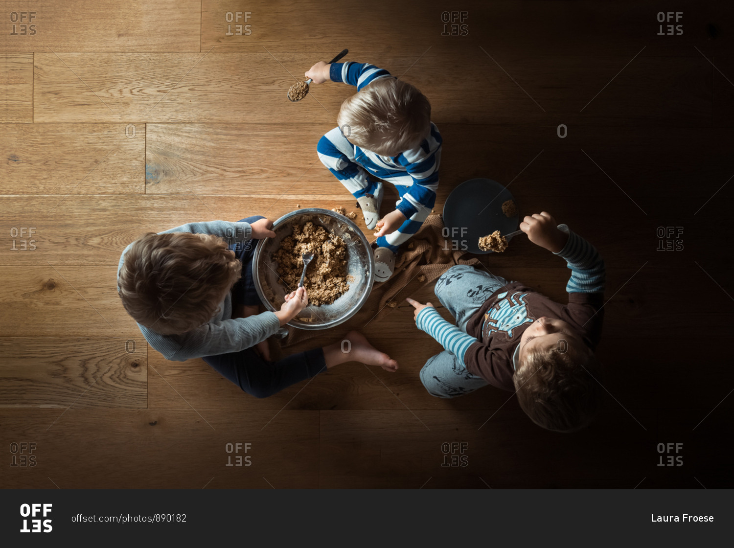 Overhead view of three little boys making and eating cookie dough
