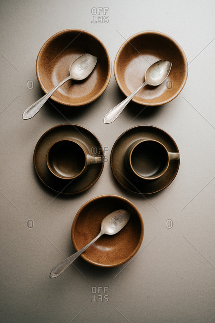 Brown mugs, saucers and bowls on light background
