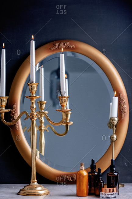 Golden candlesticks, mirror, and skincare products on a table