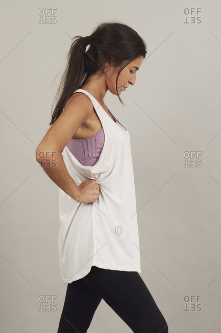Focused sportive woman stretching and warming up before training on gray background