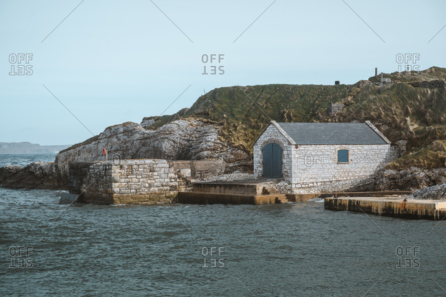Ancient stone building with doors on picturesque pier of Ballintoy harbor on rocks background