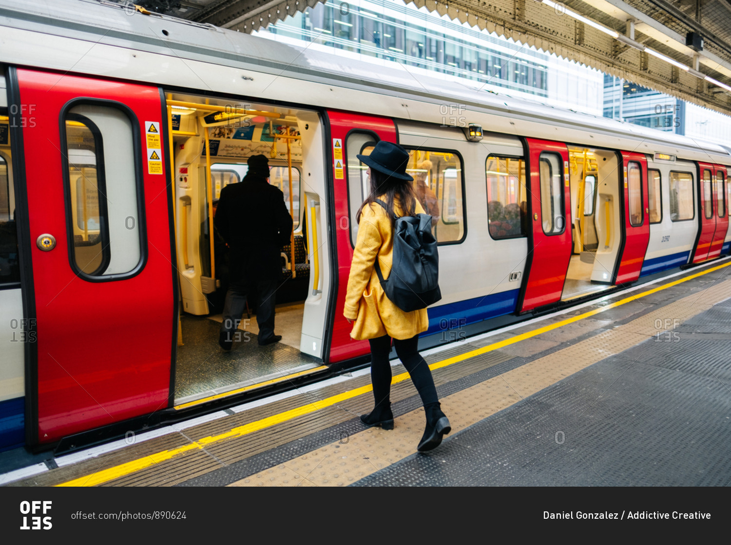 Side view of happy stylish female getting inside a underground train on platform on station in London, United Kingdom