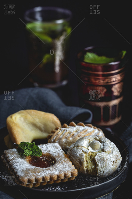 Traditional tea with mint and assorted homemade Arab sweets on dark background.