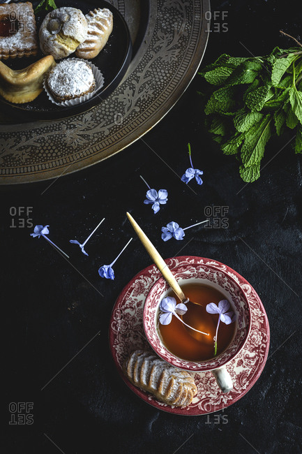 Traditional tea with mint and assorted homemade Arab sweets on dark background.