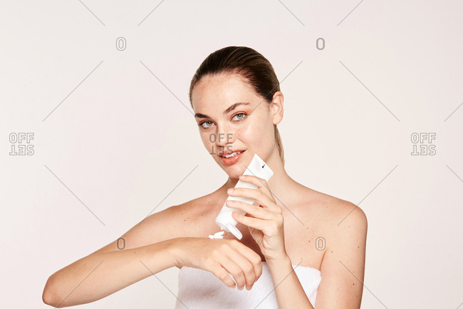 Appealing female applying moisturizing cream on hands