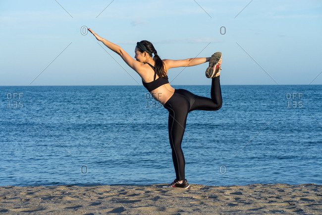 Young Woman Practicing Yoga On The Beach By The Ocean, Yoga Poses Set  Against Beautiful Background Stock Photo
