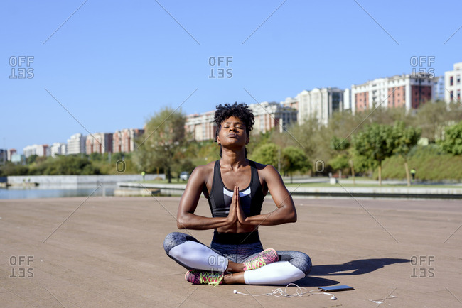 Serene and calm indian young woman in sports outfit sits in lotus pose on  mat Stock Photo by ©VadymPastukh 484409876