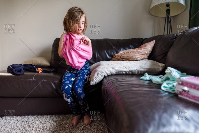 Little girl getting dressed with pink shirt in the living room