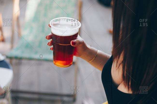 Detail of woman holding beer cup in hand during a sunny summer day outdoors. Summer music festival atmosphere.