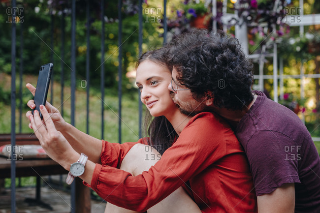 Beautiful young couple in love taking selfie with smartphone outdoors during summer