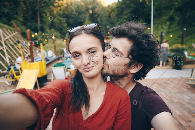 Beautiful young couple in love taking selfie on smartphone during summer music festival
