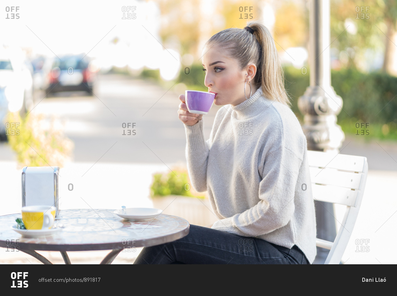 Young blonde woman having a cup of coffee on the terrace