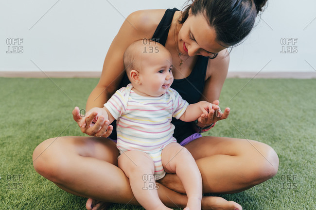 Young mother and baby exercising during mother child gymnastics