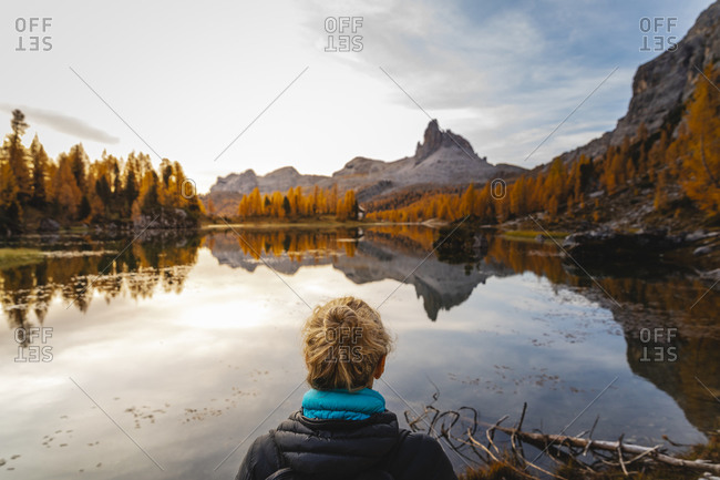 Female hiker looking at the mountain landscape with lake at the first light of the day- Dolomites Alps- Cortina- Italy