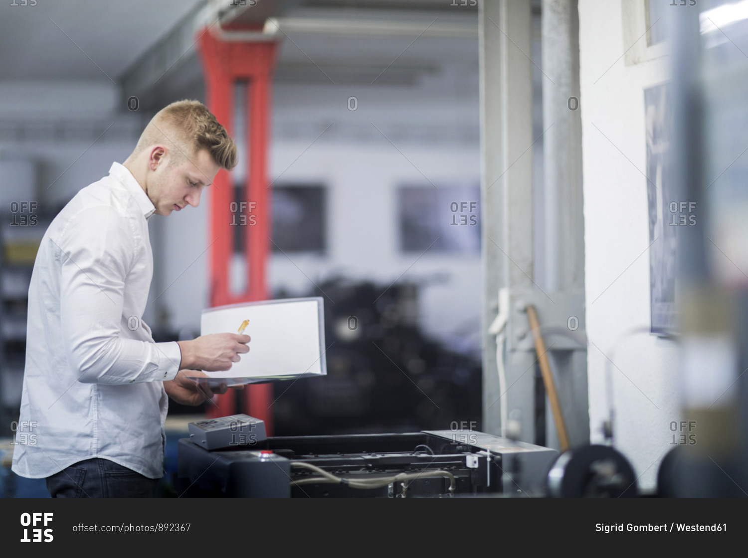 Young man checking printer in a printing company
