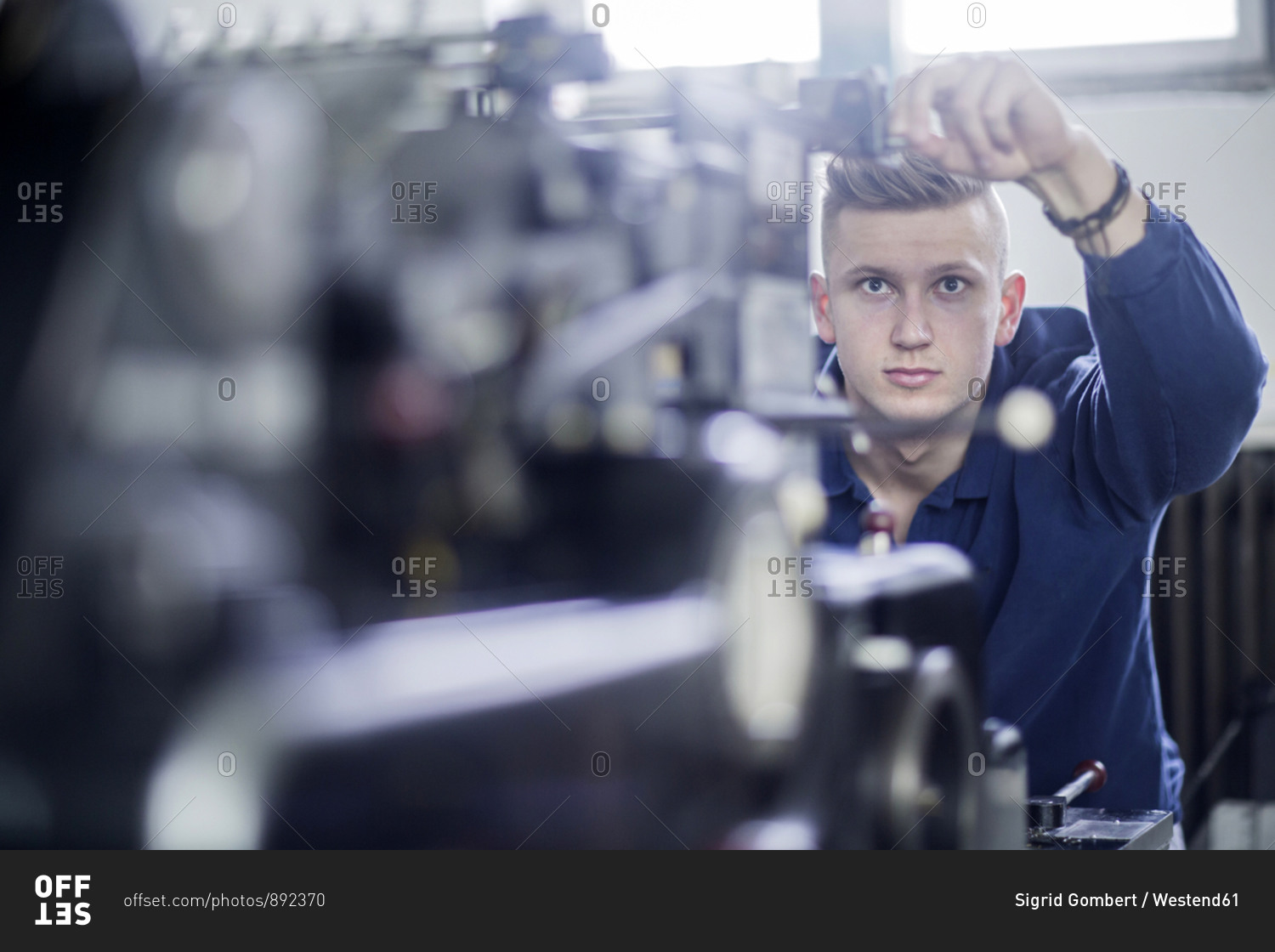 Young man adjusting a machine in a printing company