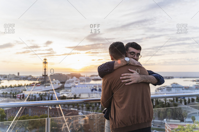 Gay couple hugging on lookout above the city with view to the port- Barcelona- Spain
