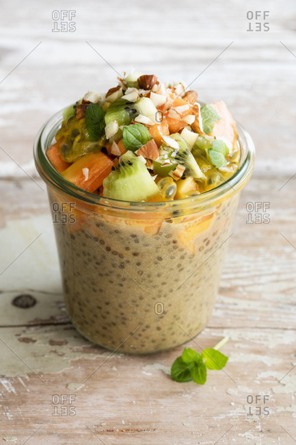 Jar of vegan pudding with chia- almond milk- persimmon- kiwi fruit- papaya- passion fruit and almonds