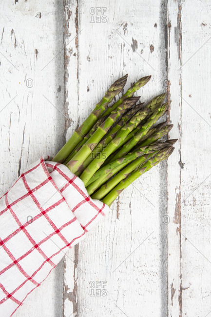 Green asparagus bunch on wicker tray on white table background