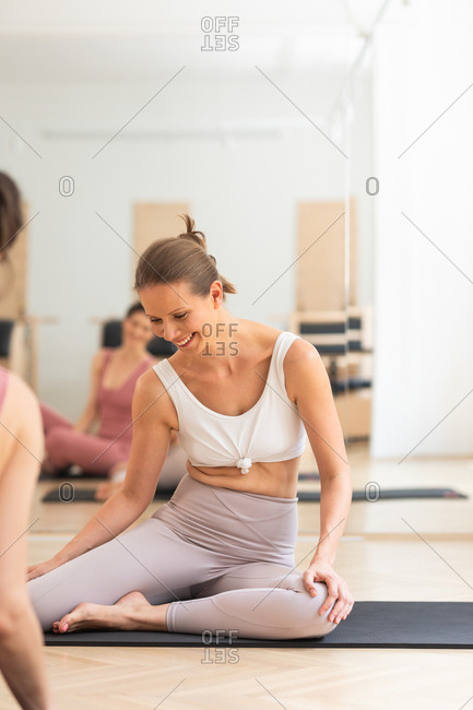 Pretty smiling woman sitting at pilates studio and smiling with instructor.