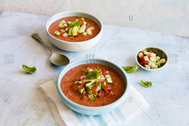 Bowls of gazpacho with fresh herbs and chopped toppings