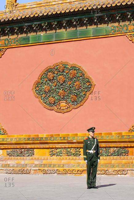 Beijing, China - March 22, 2016: Guard standing by ornate wall of The Forbidden City