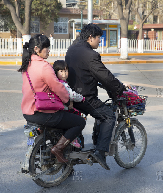 Beijing, China - March 26, 2016: Family of three on scooter in traffic ...