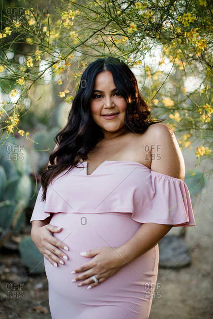 Pregnant Mom to be posing under tree with yellow flowers