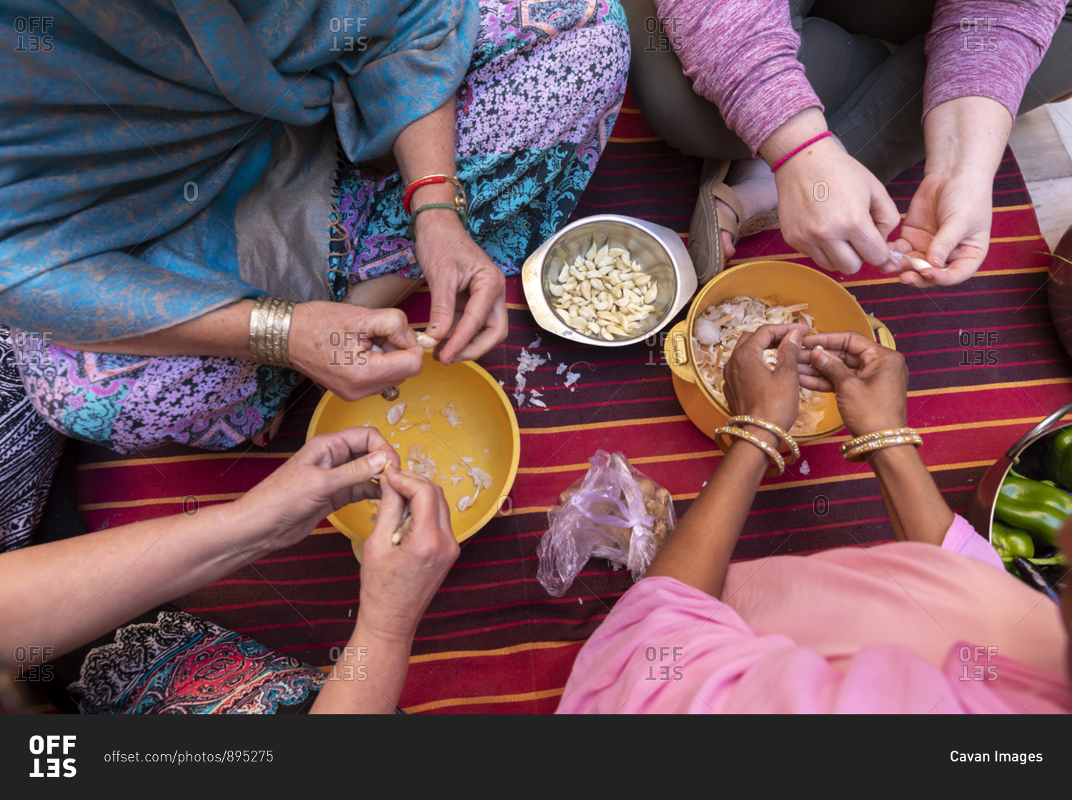A detail shot of diverse women's hands preparing garlic..