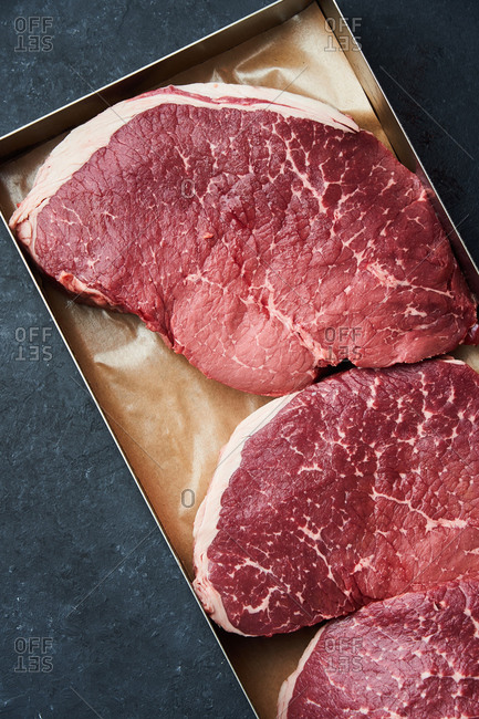 Overhead view of a tray filled with large raw steaks