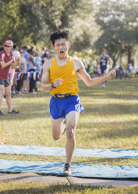 Asian high school cross country runner crosses finish line emotional