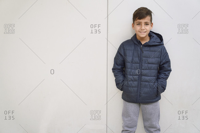 Green eyed kid with blue jacket posing in a white wall