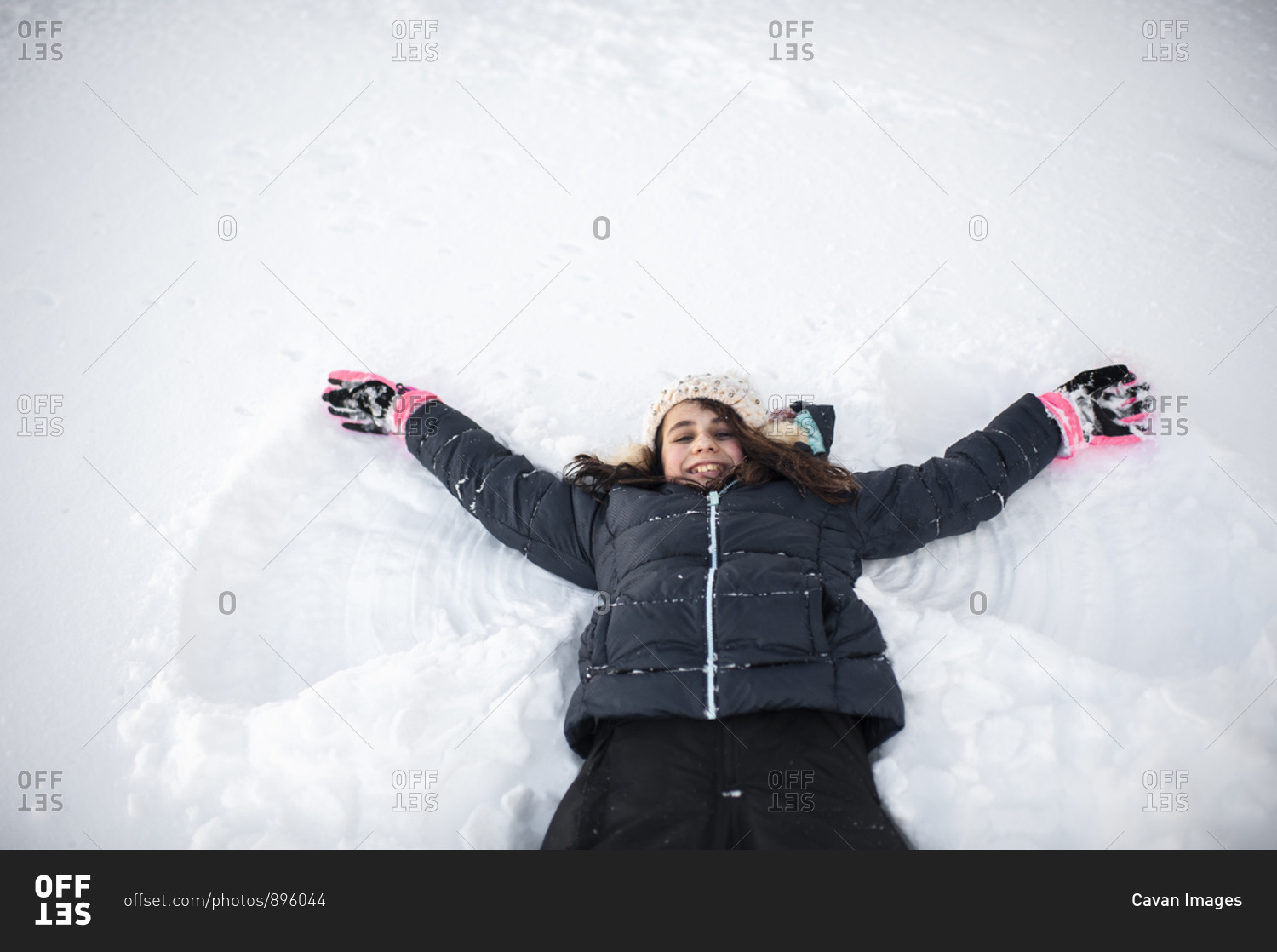 Girl smiling while making snow angel in the snow in front yard