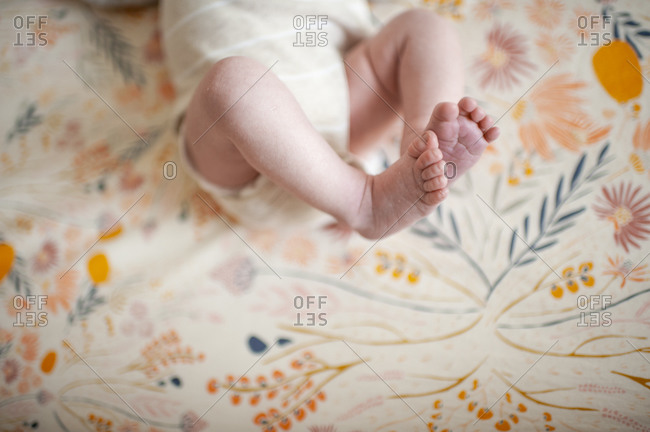 Close up of newborn feet against floral crib sheet at home