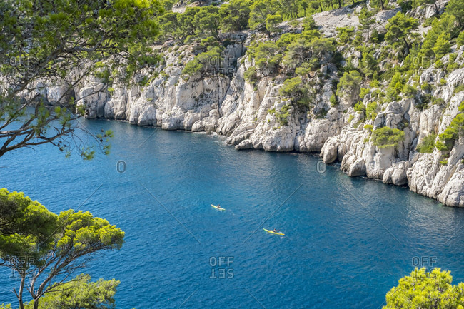 Kayakers paddling through blue water of Calanque de Port-Pin, France