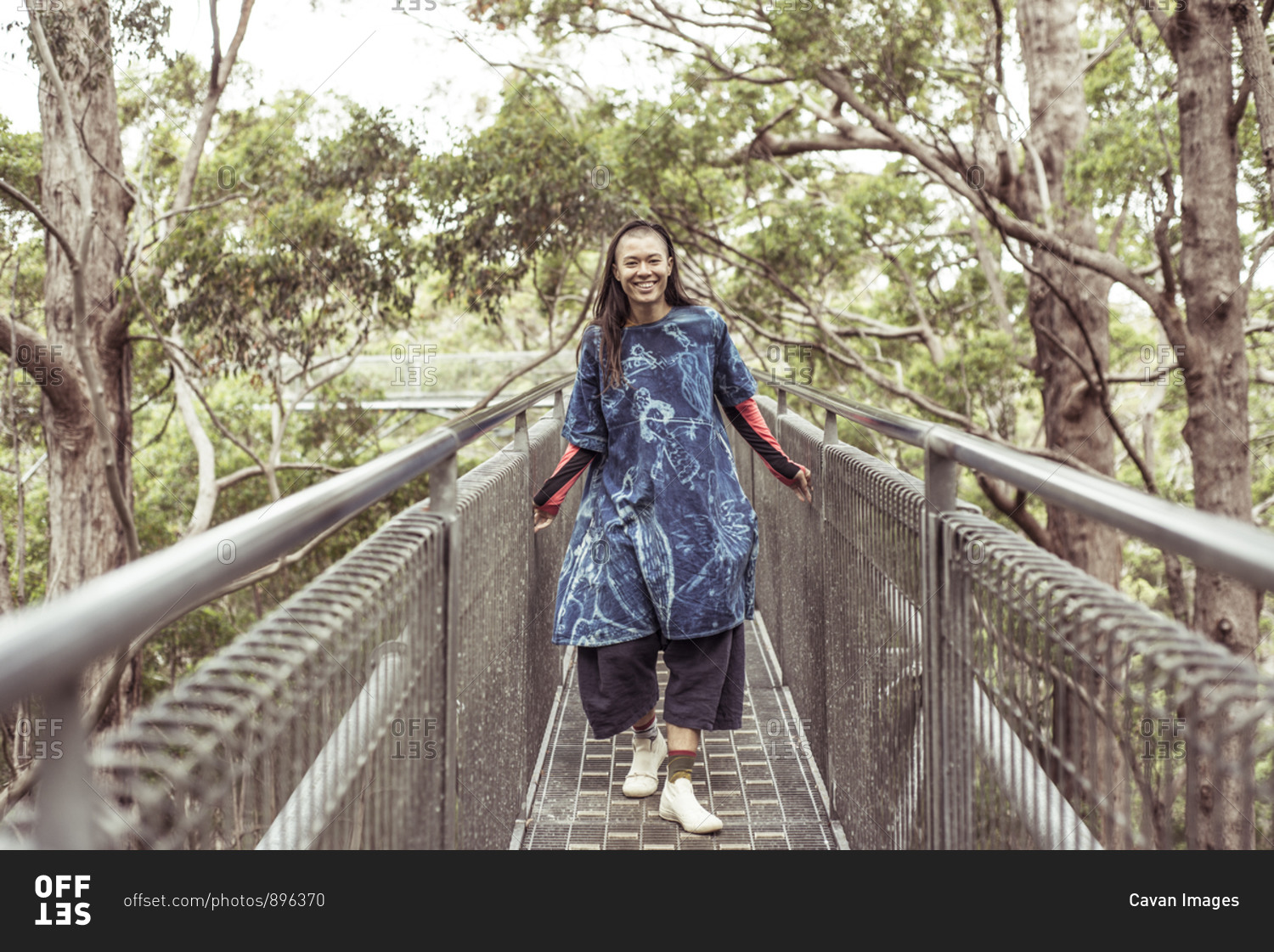 mixed race asian queer woman smiles and laughs on tree top walk