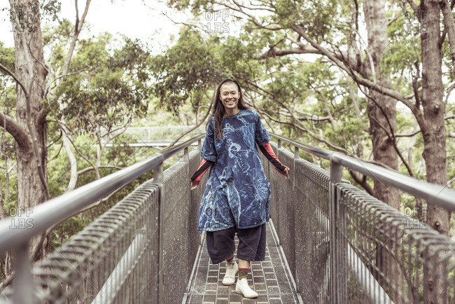 Mixed race queer woman smiles and laughs on tree top walk