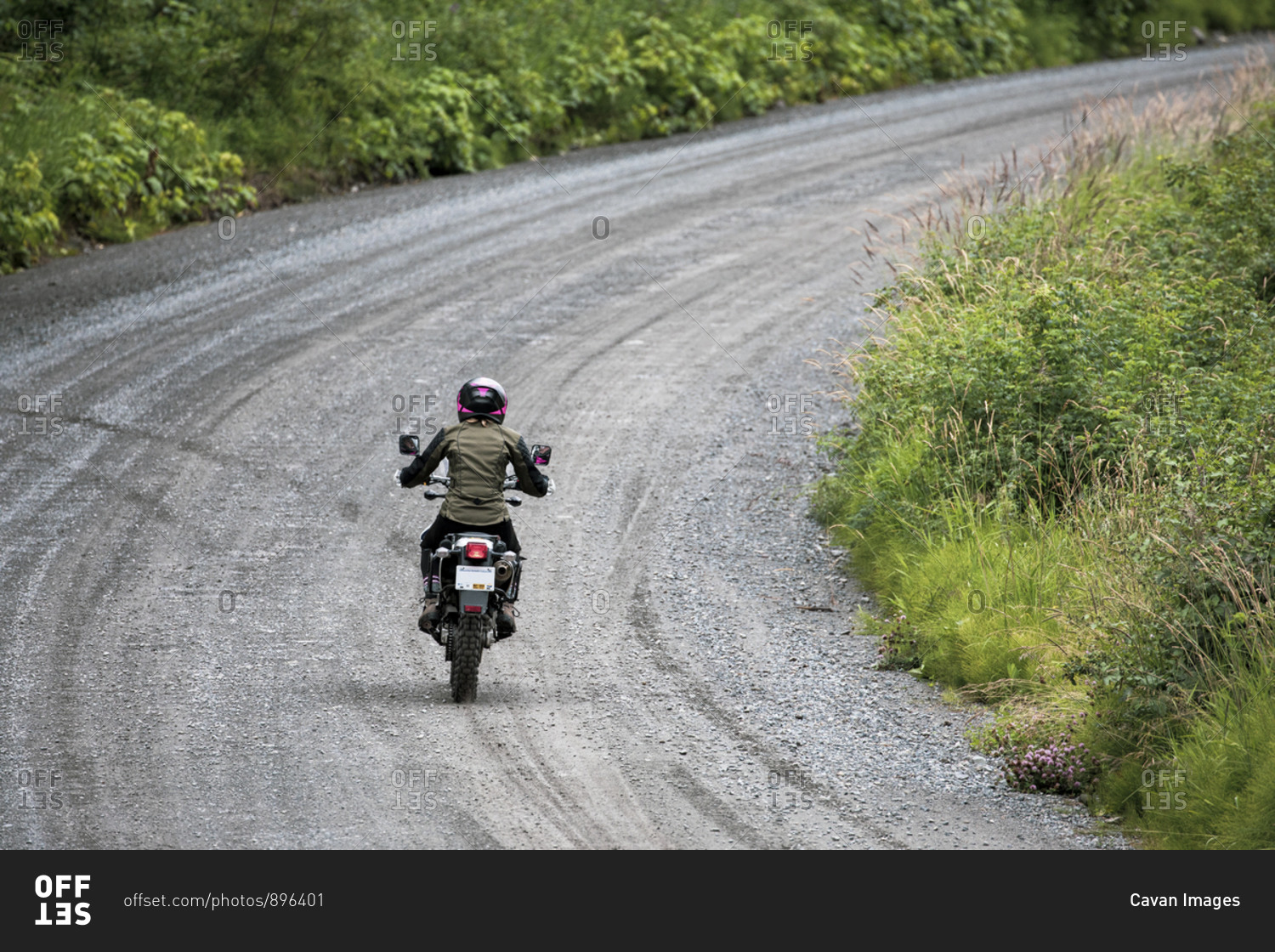 A women rides her motorcycle on a gravel road in Canada.