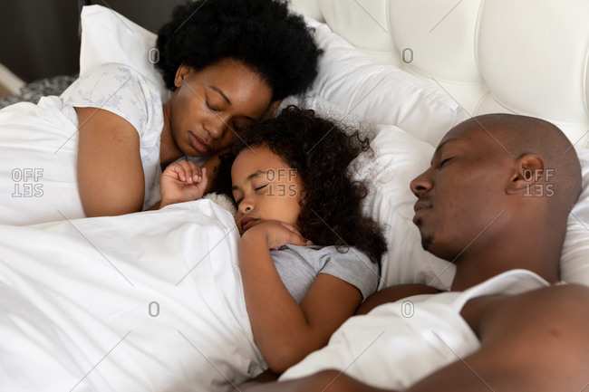 High angle view of an African American couple and their young daughter in the bedroom, lying in bed together asleep
