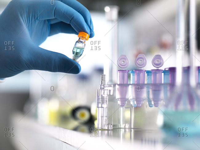 Cropped hand of scientist holding chemical formula in vial at laboratory