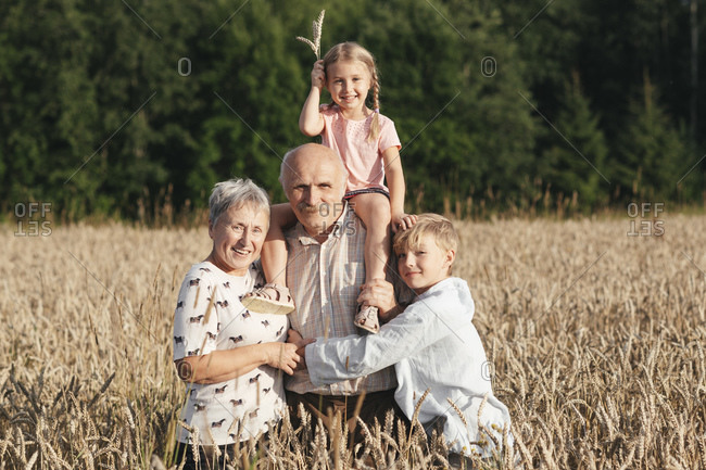 Family portrait of grandparents with their grandchildren in an oat field
