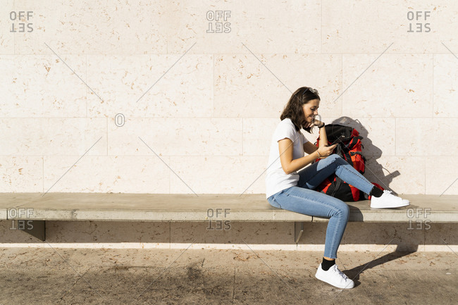 Young female backpacker with red backpack using smartphone- Verona- Italy