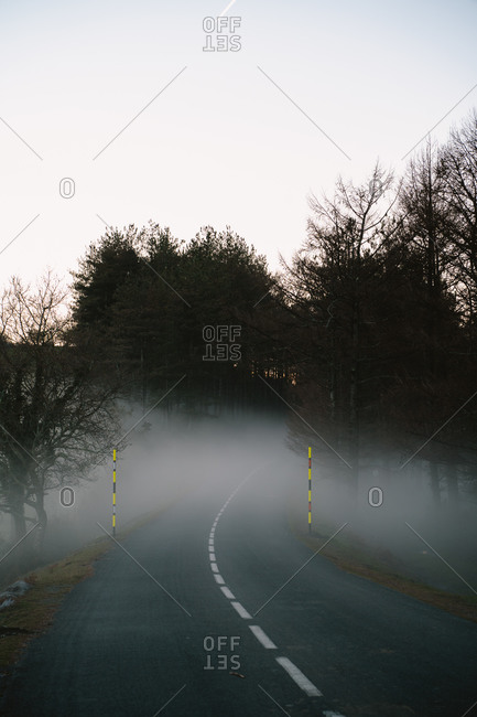 Lonely road covered by fog during sunset