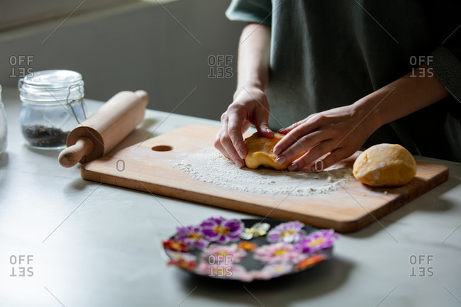 Woman making cookies with primula petals at kitchen table.