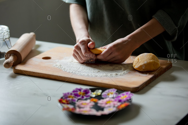 Woman making cookies with primula petals at kitchen table.