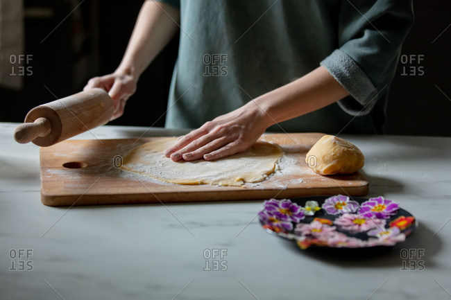 Woman making cookies with primula petals at kitchen table.
