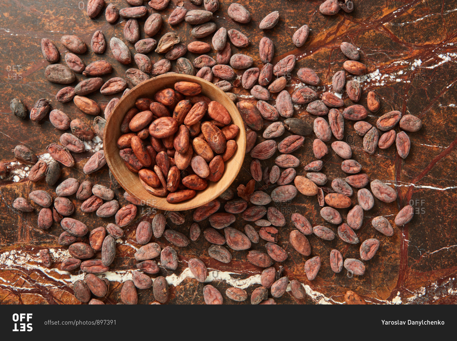 Freshly dried natural organic cocoa beans in a wooden bowl on a cacao peas background